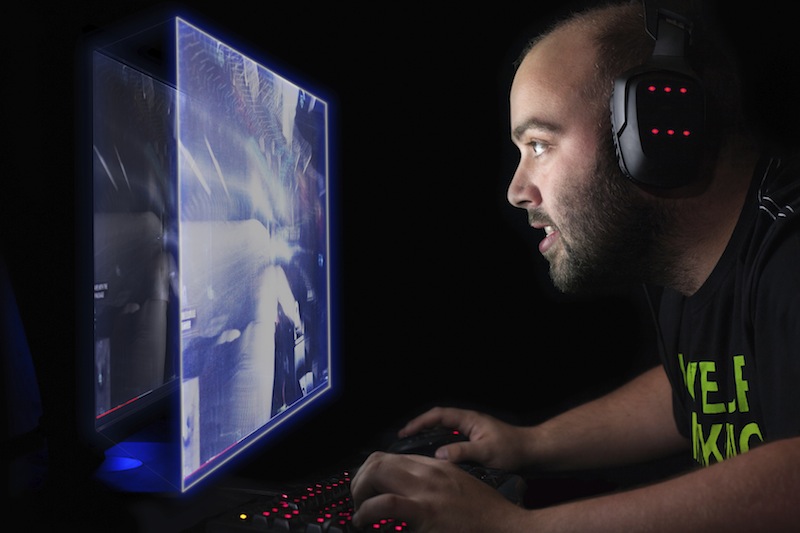 Male gamer wearing headphones while looking at a computer screen.