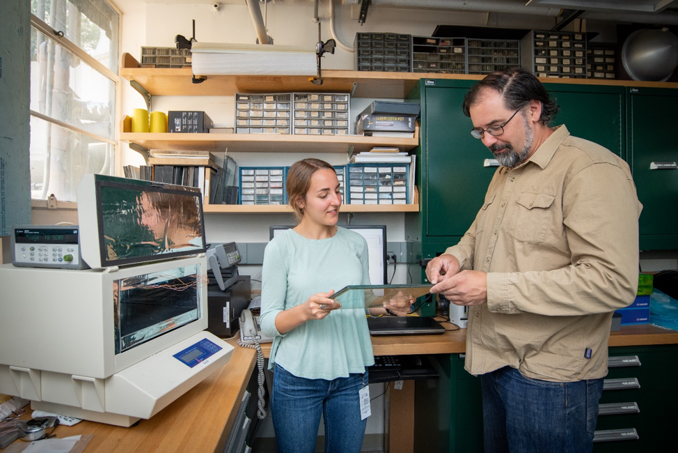 Hannah Moring and Howdy Goudey prepare to test the thermal conductivity of a vacuum insulated window pane sample using the LaserComp machine (shown, left).